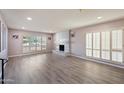 Bright living room with plantation shutters, neutral walls, a fireplace and wood flooring at , Glendale, AZ 85302