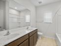 Bright bathroom featuring a double sink vanity, large mirror, and a shower-tub combination at 17761 W Getty Dr, Goodyear, AZ 85338