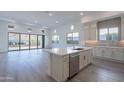 Bright, modern kitchen with white cabinets, a large island, stainless steel appliances, and wood flooring at 21436 W Meadowbrook Ave, Buckeye, AZ 85396