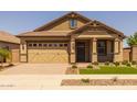 Inviting home exterior featuring a well-manicured lawn, brick accents, and a spacious two-car garage at 23162 E Canary Way, Queen Creek, AZ 85142