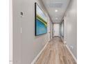 Hallway with neutral-toned walls, light wood-look flooring, and an eye-catching art piece at 2637 N 195Th Dr, Buckeye, AZ 85396