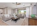 Bright living room featuring stylish gray sofas, a modern coffee table, and sliding doors to outdoor space at 2637 N 195Th Dr, Buckeye, AZ 85396