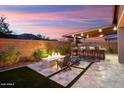 Relaxing backyard featuring a fire pit, built-in seating, and desert landscaping at sunset at 32268 N 133Rd Ln, Peoria, AZ 85383