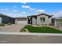 Charming home with a well-maintained lawn, stone accents, and a paved driveway leading to a two-car garage at 32268 N 133Rd Ln, Peoria, AZ 85383