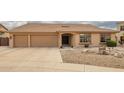 This inviting home showcases a three-car garage and low maintenance front yard with decorative rocks and mature landscaping at 4909 W Pedro Ln, Laveen, AZ 85339
