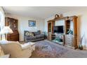 Comfortable living room featuring a large wooden entertainment center, plush sofa, and a patterned area rug at 6913 W Wilshire Dr, Phoenix, AZ 85035