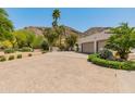Long private driveway leading to a three car garage with desert landscaping, mountain views, and mature trees at 7921 N 54Th St, Paradise Valley, AZ 85253