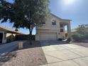 Two story home with neutral colored paint, a two car garage, mature landscaping, and an expansive driveway at 12571 W Clarendon Ave, Avondale, AZ 85392