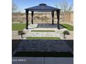 This landscaped backyard features a gazebo, artificial turf, and a decorative gravel border at 1702 N 214Th Ln, Buckeye, AZ 85396