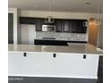 Modern kitchen with sleek dark cabinetry, stainless steel appliances and a white countertop island at 1702 N 214Th Ln, Buckeye, AZ 85396