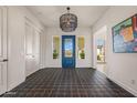 Bright foyer featuring a decorative blue door, tile flooring and chandelier at 17396 W Crawfordsville Dr, Surprise, AZ 85388