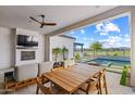 Inviting outdoor patio with fireplace, TV, dining table, and a beautiful view of the pool and backyard at 17396 W Crawfordsville Dr, Surprise, AZ 85388