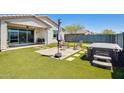 Landscaped backyard with artificial turf, covered patio, outdoor seating area, and a hot tub at 2813 W Apollo Rd, Phoenix, AZ 85041