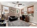 Cozy home office with exposed brick wall, a ceiling fan, and natural light from the windows at 3272 E Tyson St, Gilbert, AZ 85295