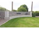 A stone community sign sits on a lush green lawn with vibrant flowers and mature landscaping at 3306 E Jaeger Cir, Mesa, AZ 85213