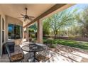 Relaxing covered patio with ceiling fan, table and chairs, and a view of the lush backyard at 5813 E Ashler Hills Dr, Cave Creek, AZ 85331