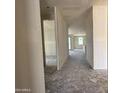 Unfinished hallway with primer walls and concrete flooring with an entrance to an unfinished room with a view of a window at 9540 W Parkway Dr, Tolleson, AZ 85353