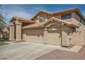 Tan two-story home featuring a three-car garage and desert landscaping at 514 E Vaughn Ave, Gilbert, AZ 85234