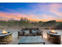 Relaxing backyard patio features comfortable seating, fire pits, and desert landscaping against a vibrant sunset backdrop at 7145 E Cuernavaco Way, Gold Canyon, AZ 85118