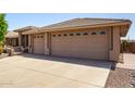 Spacious three-car garage with desert landscaping along the driveway at 10903 E Ocaso Ave, Mesa, AZ 85212