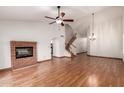 Bright living room features a brick fireplace, ceiling fan, wood floors, and stairs to the second floor at 11243 E Jenan Dr, Scottsdale, AZ 85259
