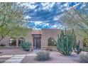 Charming tan home featuring desert landscaping with cacti, arched windows, and a stone pathway leading to the front door at 12646 N 80Th Pl, Scottsdale, AZ 85260