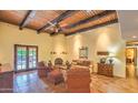 Bright living room featuring a wood-beam ceiling, fireplace, and access to the outdoor space at 12646 N 80Th Pl, Scottsdale, AZ 85260