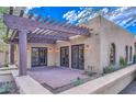 Covered patio area with brick flooring, a wooden pergola, double doors, and exterior lighting fixtures at 12646 N 80Th Pl, Scottsdale, AZ 85260
