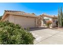 Single story home showcasing the front two car garage and tile roof and the private gated courtyard at 14207 W Kiowa Trl, Surprise, AZ 85374