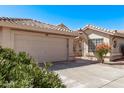Single story home showcasing the front two car garage and tile roof and the private gated courtyard at 14207 W Kiowa Trl, Surprise, AZ 85374