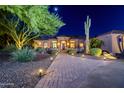 Charming home exterior with desert landscaping, featuring a brick walkway and nighttime illumination at 1423 E Breezy Ct, Phoenix, AZ 85086