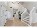 Bright foyer with a striking staircase, light wood floors, and a view into the main living space at 14862 N 90Th Pl, Scottsdale, AZ 85260