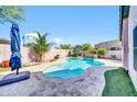 Backyard pool with travertine decking, a waterfall feature, and mature palm trees at 21605 N 48Th Pl, Phoenix, AZ 85054