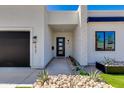 Modern home's front entrance featuring a black door, stone accents, and desert landscaping at 2927 E Osborn Rd, Phoenix, AZ 85016