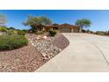 Front exterior of desert home with mature desert landscaping and a long driveway at 42145 N Fairgreen Ct, Anthem, AZ 85086
