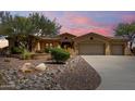 Southwest home featuring a three-car garage and desert landscaping, including decorative rocks and cacti at 42145 N Fairgreen Ct, Anthem, AZ 85086
