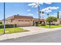 Well-maintained home featuring a spacious driveway, attached garage, and manicured front yard with mature trees at 10601 W Hutton Dr, Sun City, AZ 85351