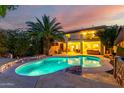 Stunning outdoor pool and patio area with lush landscaping, palm tree and a beautiful sunset view at 14228 W Weldon Ave, Goodyear, AZ 85395