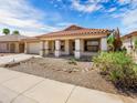 Single story home features tile roof, covered porch, xeriscaped front yard, and low-maintenance landscaping at 17210 N Cassi Dr, Surprise, AZ 85374