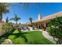 Backyard featuring a pool, lush lawn, mature palm trees, and a covered patio area at 18907 N 92Nd Way, Scottsdale, AZ 85255