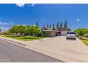 Single-story home with a well-maintained lawn, mature trees, and a basketball hoop on a large driveway at 1907 E Huber St, Mesa, AZ 85203