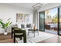 Bright living area with a plush white sofa, modern decor, and sliding glass doors to outdoor patio at 2300 E Campbell Ave # 106, Phoenix, AZ 85016