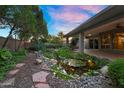 Serene backyard featuring a tranquil koi pond, stone pathway, and lush foliage at 315 E Marlette Ave, Phoenix, AZ 85012