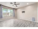 Spacious bedroom with a large window, wood-look flooring and ceiling fan at 34710 N 27Th Ave, Phoenix, AZ 85086