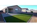 Landscaped backyard with synthetic grass, a paved patio, block wall fencing, and a covered patio at 37049 N Lokai Dr, San Tan Valley, AZ 85140