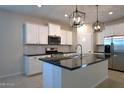 Bright kitchen with white cabinets, a granite island, stainless steel appliances, and modern pendant lighting at 37049 N Lokai Dr, San Tan Valley, AZ 85140