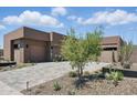 Modern home with desert landscaping featuring native plants and a spacious driveway leading to a multi-car garage at 37200 N Cave Creek Rd # 1013, Scottsdale, AZ 85262