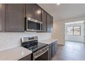 Modern kitchen with stainless steel appliances, white backsplash, and stylish dark cabinetry at 39965 W Bunker Dr, Maricopa, AZ 85138