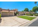 Attractive single-story home with a long driveway, well-manicured lawn, a three-car garage, and Southwestern style architecture at 9847 E Michigan Ave, Sun Lakes, AZ 85248
