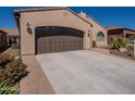 Spacious three-car garage with a wide driveway and elegant exterior lighting at 132 E El Prado Dr, Queen Creek, AZ 85140